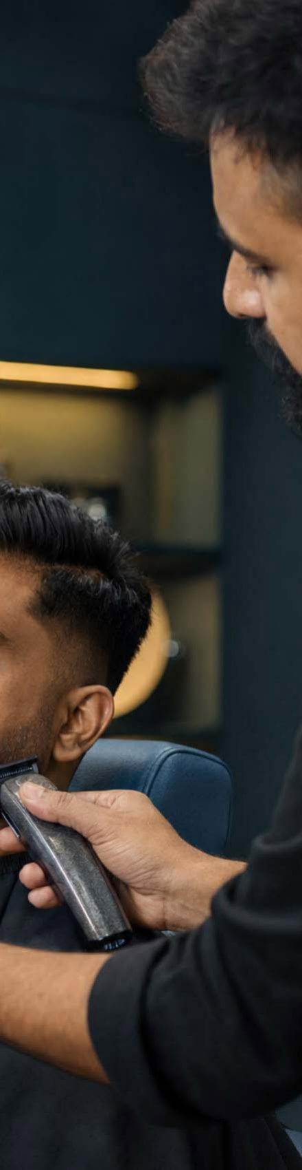 Barber trimming a client's beard with precision clippers